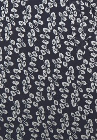Tejido de color azul marino con un patrón repetido de hojas blancas, adornado con vides delgadas y formas de hojas detalladas, creando un diseño floral texturizado.
