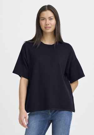 Marineblaues übergroßes T-Shirt mit kurzen Ärmeln, gerippter Textur, rundem Ausschnitt und geradem Saum, kombiniert mit Jeans.