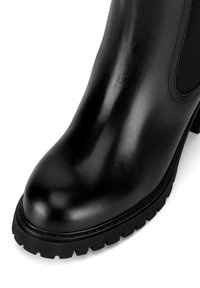 Čierna kožená členková topánka s hladkým povrchom, zaoblenou špičkou, elastickými bočnými panelmi a štruktúrovanou gumovou podrážkou s dezénom.