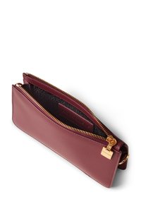 Portefeuille en cuir bordeaux avec fermeture éclair et quincaillerie dorées. Dispose d'un intérieur texturé et d'un design plat. Compact et polyvalent pour les essentiels.