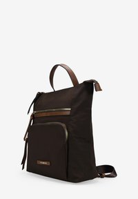 Mochila de nylon marrón con acentos de cuero, que cuenta con múltiples bolsillos con cremallera y un diseño plano. Correa ajustable y asa superior para llevar.