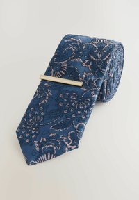 Cravate bleu marine avec un motif floral en rose et bleu foncé, fabriquée en tissu texturé, avec une pince à cravate en couleur or.