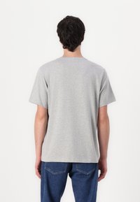 Tricou gri cu mâneci scurte și decolteu tip crew, realizat dintr-un material moale. Prezintă o croială lejeră, cu detalii de cusătură minime.