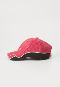 Rød baseballcaps med en litt buet skjerm, svart underside og hvite s�ømmer. Vintage tekstur med subtil slitasje på stoffet.