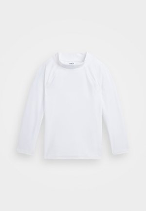 Camisa blanca de manga larga hecha de tejido suave. Presenta un cuello redondo y un discreto detalle de costura en las mangas y el dobladillo. Etiqueta con el logo visible.