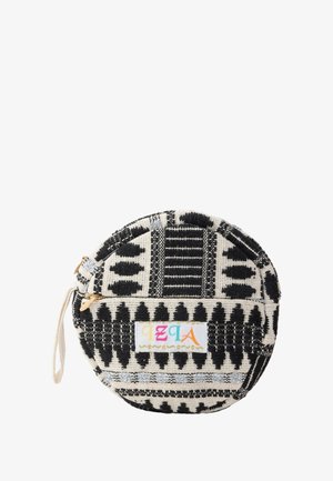 Okrągła torba materiałowa z czarno-białym geometrycznym wzorem, z suwakiem i małą dekoracyjną etykietą. Teksturowana powierzchnia.