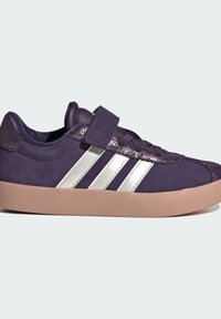 Fialové semišové tenisky se stříbrným trojproužkem, suchým zipem a texturovanými prvky na patě. Obsahují růžovou gumovou podrážku.