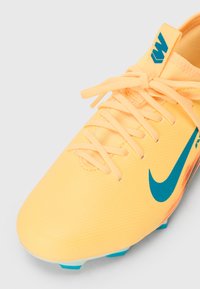 Jasnożółty but sportowy z gładką syntetyczną cholewką, z niebieskim logo w kształcie ósemki, fakturowaną powierzchnią i turkusowym akcentem na podeszwie.