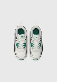 Nike Air Max sportcipők, fehér bőr felsőrésszel, fekete részletekkel és zöld kiemelésekkel. Vastag talp, párnázott sarok és fűzős kialakítás.