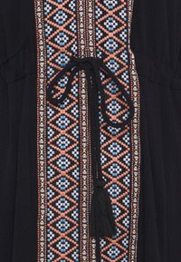 Schwarzes Kleid aus Stoff mit aufwändiger, bunter Stickerei in pinken, blauen und weißen geometrischen Mustern entlang der Mitte, mit einem Bindeband und Quaste.