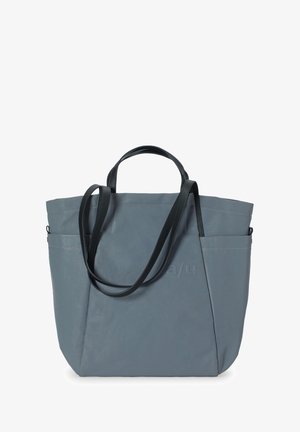 Šedá taška přes rameno vyrobená z hladkého materiálu, s dvojitými černými uchy, boční kapsou a prošívanými detaily. Minimalistický design se zvýrazněním loga.