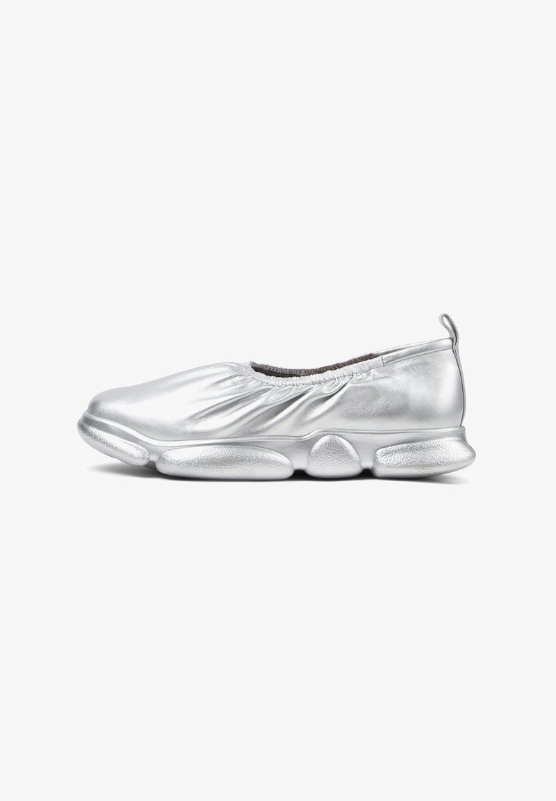 Silverslipsko med en samlad, strukturerad ovansida och en vadderad yttersula med rundade, avlånga kuddar. Den lätta designen förbättrar flexibiliteten.