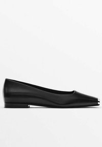 Chaussure plate en cuir noir avec bout pointu et détail métallique à la pointe, dotée d'un petit talon et d'une finition lisse.