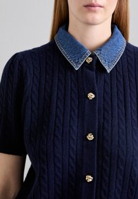 Pletený námořnický svetr s denimovým límcem, kabelkovou texturou a zlatými růžovými knoflíky po celé přední části.