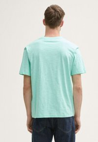 Camiseta de manga corta verde menta con un corte holgado. Hecha de una tela ligera, con un cuello redondo y dobladillo recto, textura visible.