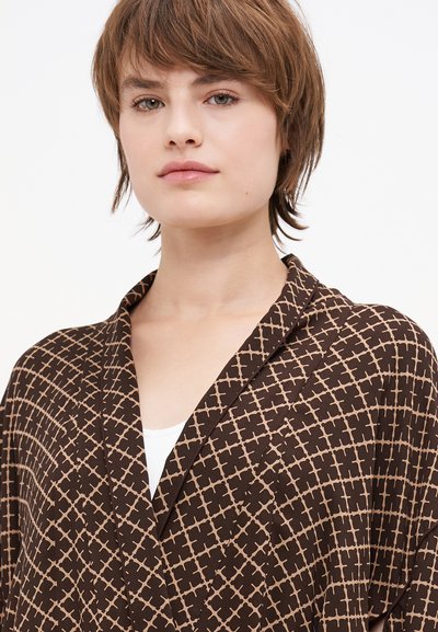 Kimono marrón con un diseño geométrico en beige, que cuenta con un cuello tipo chal y una textura suave, drapeándose alrededor de los hombros.