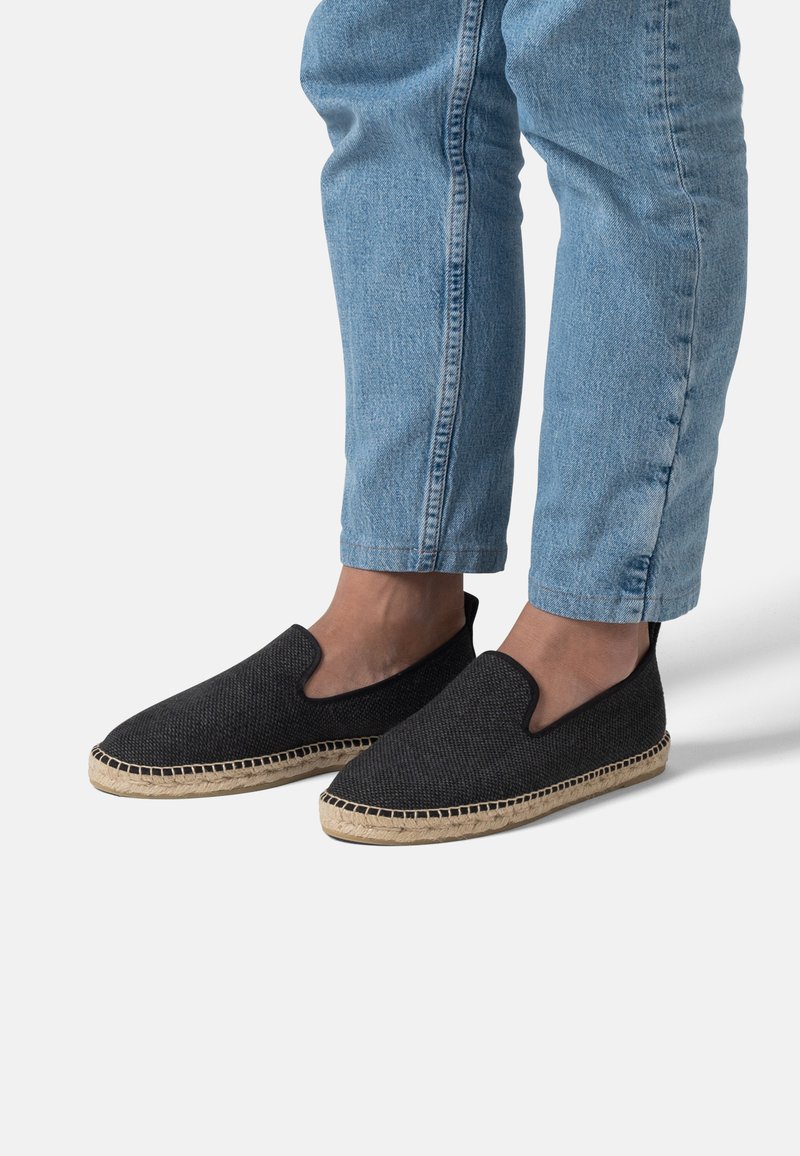 Černé espadrilky na slip-on s texturovaným textilním svrškem a tkanou juteovou podešví. Uvolněný design, zakřivený okraj a elastická boční část pro snadné nošení.