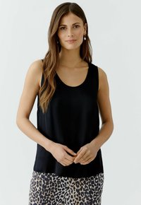 Schwarzes ärmelloses Tanktop aus glattem, leichtem Stoff. Mit einem runden Halsausschnitt und einem lässigen Schnitt, kombiniert mit einer leopardenbedruckten Hose.