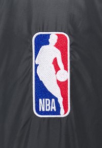 Silhouette d'un joueur de basketball dribblant le ballon, sur un fond vertical bleu et rouge avec le texte « NBA » en dessous.