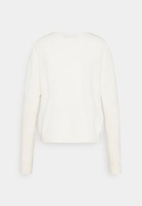 Jasno beżowy, długi sweter dzianinowy z okrągłym dekoltem i prostym wykończeniem. Gładka tekstura, minimalistyczny design, brak widocznych wzorów lub ozdób.