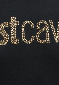 Μαύρο ύφασμα με χρυσά στρας που σχηματίζουν μερικά γράμματα μιας λέξης, με πέτρες σε σχήμα κύκλου διαφόρων μεγεθών.