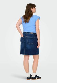 Modra rebrasta majica z nabranimi rokavi, v kombinaciji s temnim denim krilom v stilu svinčnika, ki ima zasekane robove in dva zadnja žepa.
