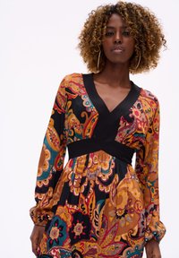 Bloemmotief jurk met lange mouwen, een diepe V-hals, een aansluitende zwarte tailleband en levendige kleuren in paisleymotieven.