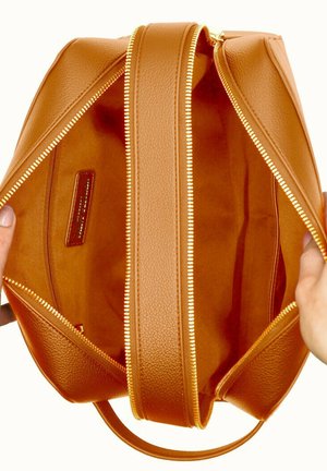 Sac en cuir marron avec une texture lisse, doté de deux zips, d'un intérieur ouvert et d'un design simple. Les accents comprennent des détails de zips dorés.