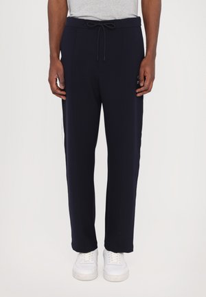 Pantalones jogger para hombre en azul marino con cintura ajustable, bolsillos laterales y logos blancos; tejido suave y corte ajustado con dobladillo elástico.