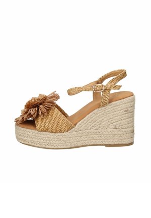 Sandalo con zeppa intrecciata color cuoio con piattaforma in corda intrecciata, cinturino alla caviglia con fibbia, punta aperta e fiore decorativo in rafia sulla fascia anteriore.