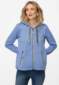 Ljusblå zip-up hoodie i texturerad tyg, med huva, svarta dragsnören och två zip-fickor framtill.