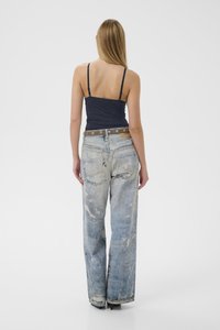 Marineblå tanktop og slidte lyseblå vidde-bukser med brunt bælte med sølvnitter. Model vist bagfra.