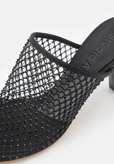 Černé otevřené muly mají síťovinový svršek s mřížkovým vzorem, zdobené malými korálky, a pevný černý podpatek. Hladká vnitřní podšívka.