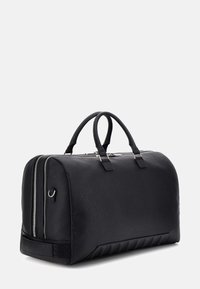 Borsa da viaggio in pelle nera con finitura testurizzata, dotata di due scomparti con cerniera, manici robusti e un dettaglio a coste alla base.