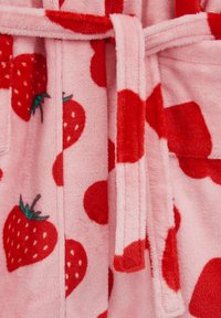 Rožinės spalvos flisinis chalatas su raudonais braškių raštais ir didesniais raudonais taškučiais, turintis derantį dirželį ir minkštą tekstūrą.