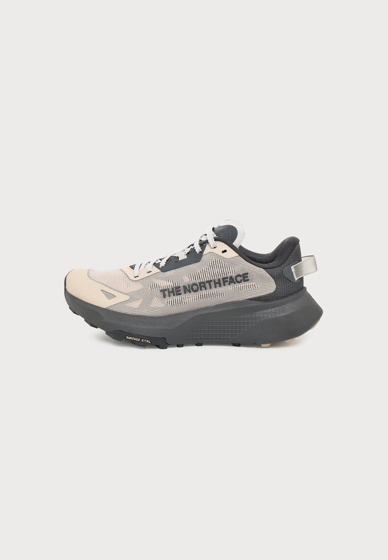 Baskets The North Face beige et noires avec semelle épaisse, empeigne en mesh, lacets et texte de marque sur le côté, sur un fond blanc uni.