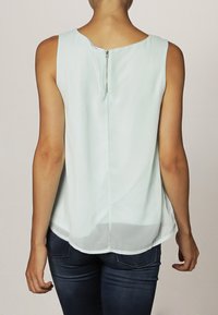 Top senza maniche di un delicato verde menta, con scollatura rotonda e zip sul retro, realizzato in un tessuto leggero e liscio, con orlo curvo.