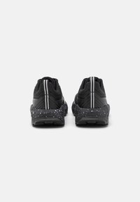 Black athletic shoes with a textured upper, featuring white stripes and a speckled sole. Designed for comfort with a flexible fit.
