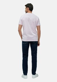 Světle růžové bavlněné tričko, krátké rukávy, kulatý výstřih, v kombinaci s tmavě modrými džíny a bílými teniskami. Viditelné detaily na zadní straně a střih.