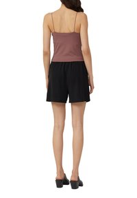 Bordeaux spaghetti strap top met een getailleerd ontwerp, gecombineerd met zwarte, losse shorts. Eenvoudige, casual look zonder zichtbare patronen.