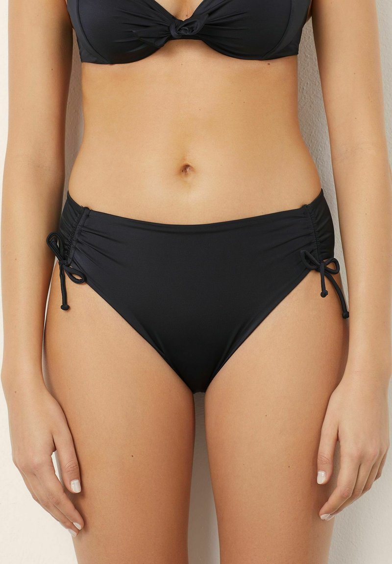 Chiloti negri cu talie înaltă, cu legături ajustabile pe laterale, textură netedă și detalii pliate pe părți.
