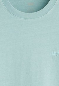 Lyseblå bomulds T-shirt med ribbet rund hals og diskret "LEV" broderi nederst til højre. Blød, glat tekstur.