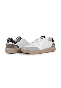 Sneaker bianche in pelle con accenti grigi e neri, caratterizzate da dettagli perforati, lacci piatti e una suola in gomma testa di moro testurizzata.
