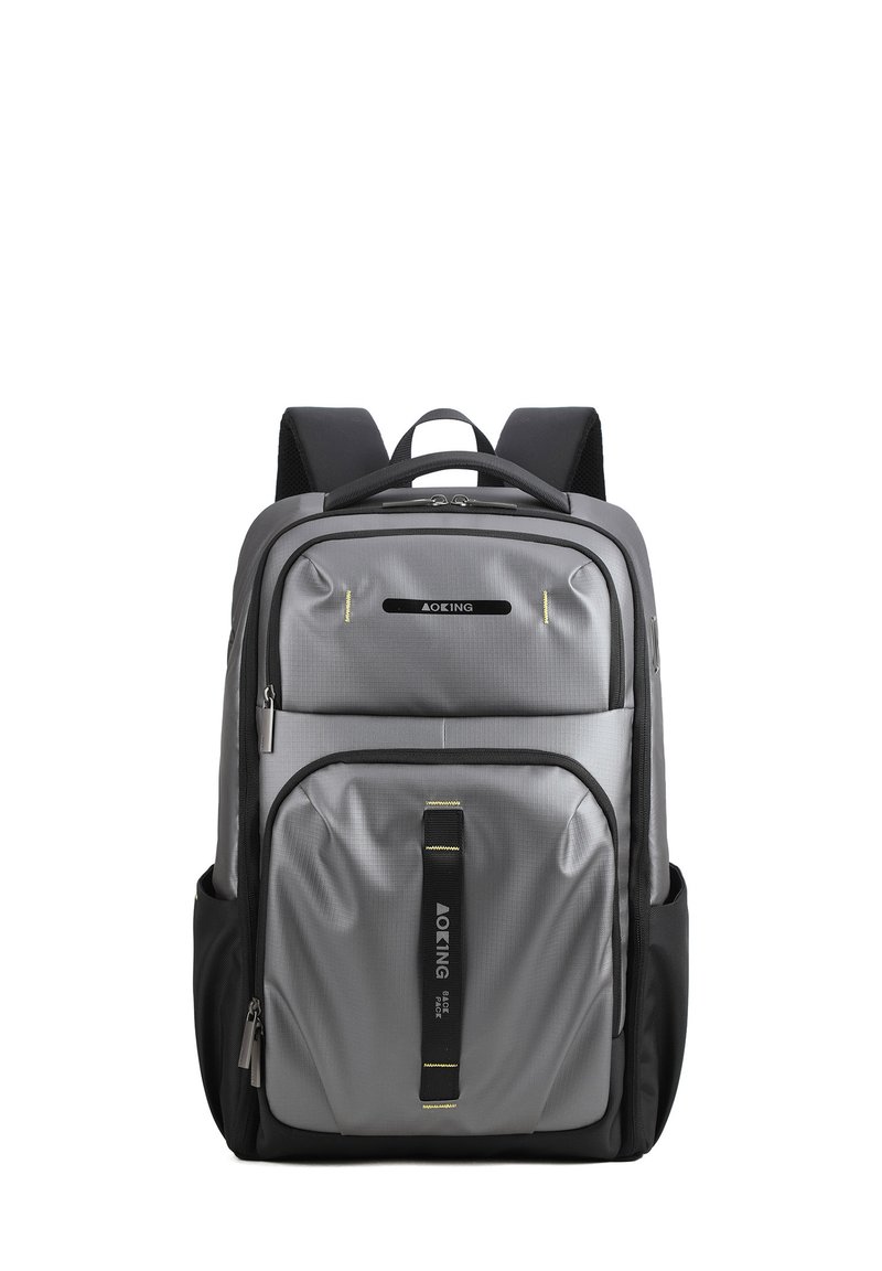 Un sac à dos gris avec une finition texturée, doté de bretelles rembourrées, de plusieurs compartiments zippés et d'une base noire. Des accents jaunes soulignent les détails.