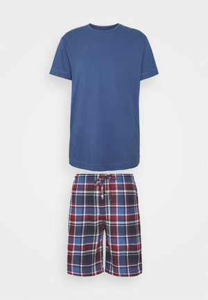 T-shirt in cotone blu con maniche corte, abbinato a pantaloni a quadri rossi, blu navy e azzurri, dotati di vita regolabile con cordino.