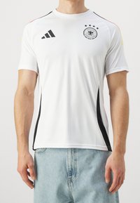 Jersey atlético blanco con detalles negros, con mangas cortas y un cuello redondo. Incluye un emblema negro y cuatro estrellas negras.