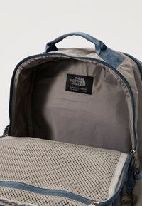 Ανοιχτό μπεζ και μπλε σακίδιο πλάτης με εσωτερική τσέπη φερμουάρ από δίχτυ και το λογότυπο The North Face στο πίσω εσωτερικό πάνελ.