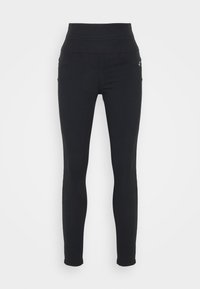 Leggings negros de cintura alta hechos de un tejido elástico, con una textura suave y dos bolsillos frontales con sutiles detalles de costura.