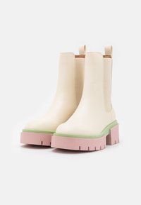 Beżowe botki sięgające kostki o gładkim wykończeniu, zielona i różowa platforma, okrągły dziób oraz pętle do łatwego zakładania. Gruba podeszwa zapewniająca przyczepność.