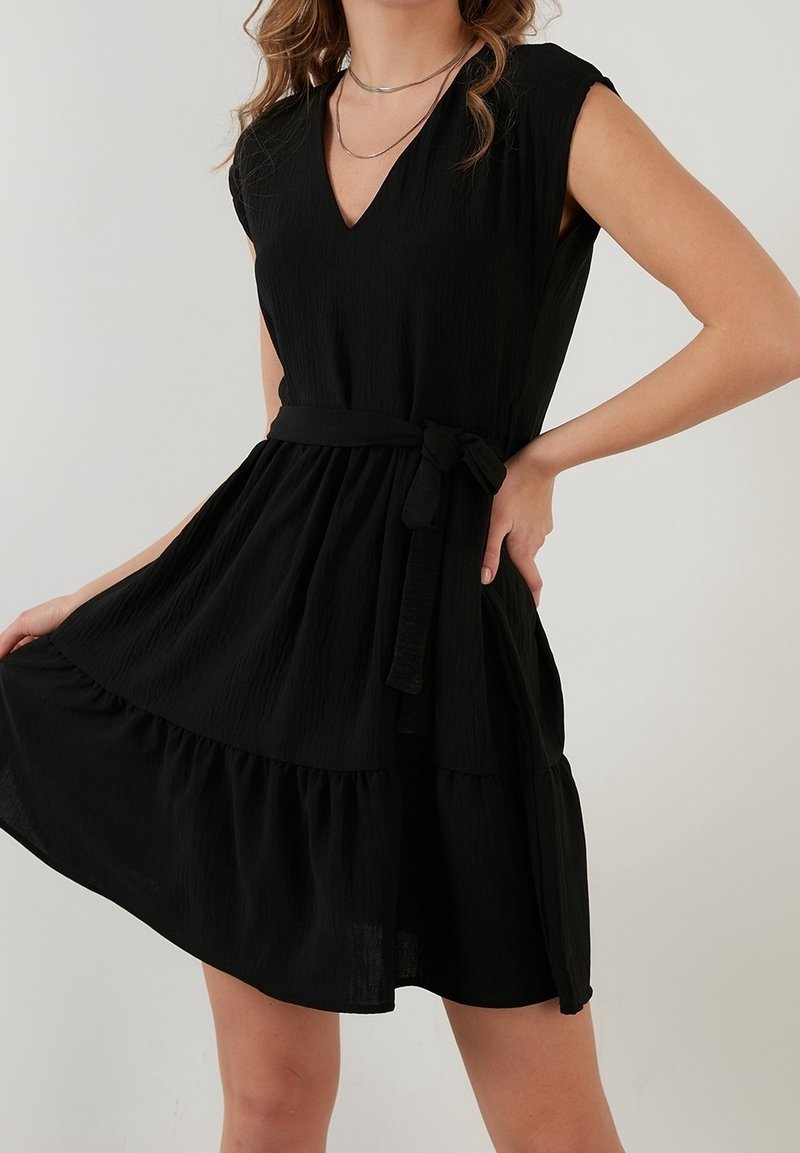 Svart kort klänning i strukturerad tyg, med v-ringning, korta ärmar, ett knytbälte i midjan och en lagerdesign på kjolen.